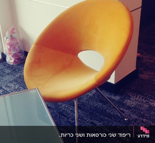 כיסא מרופד כתום ליד שולחן זכוכית